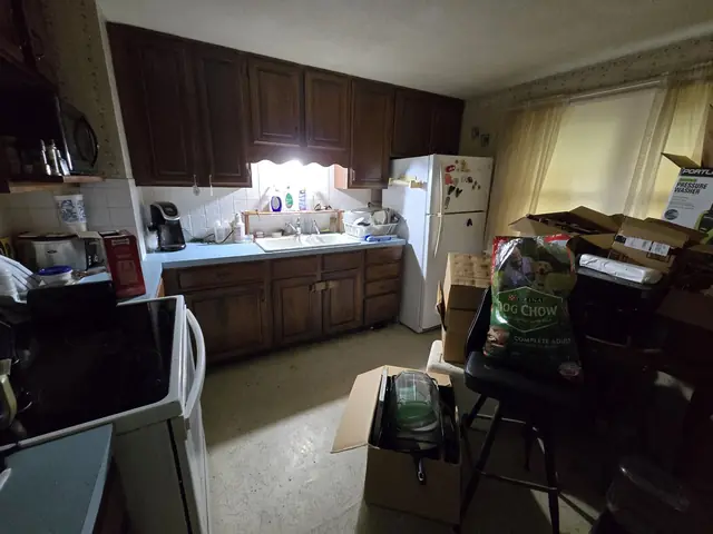 Dark kitchen with dated cabinets and boxes stacked up