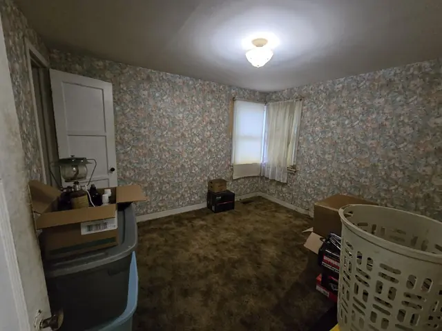 Bedroom with floral wallpaper and old brown carpet
