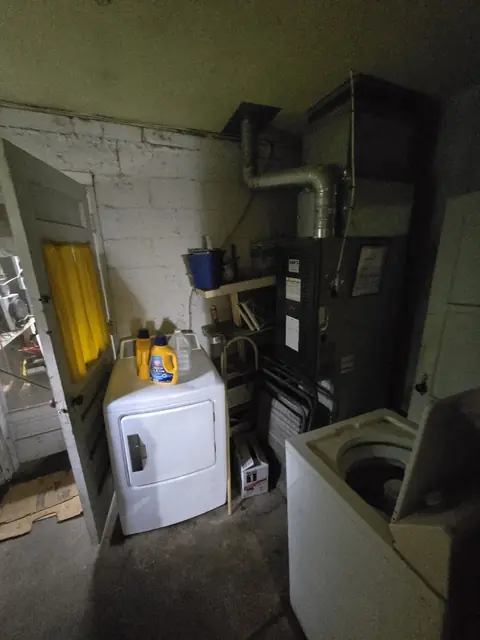 Utility room with an old furnace, washer, and dryer