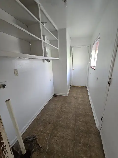 Back hall with damaged trim and debris around a pipe