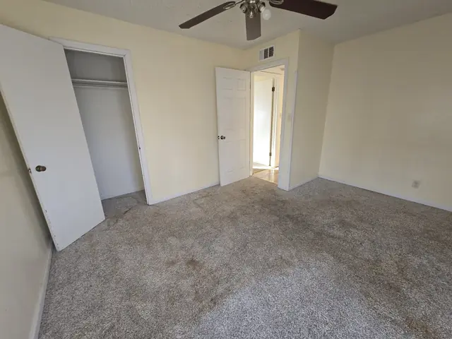 Bedroom with stained carpet and an open closet