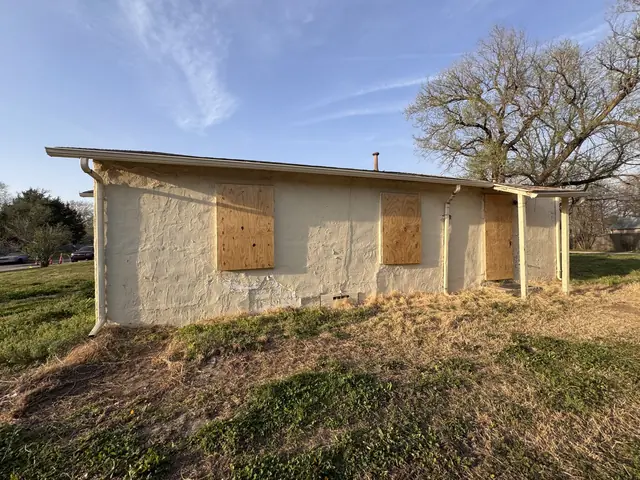 Side of the house with three boarded-up windows