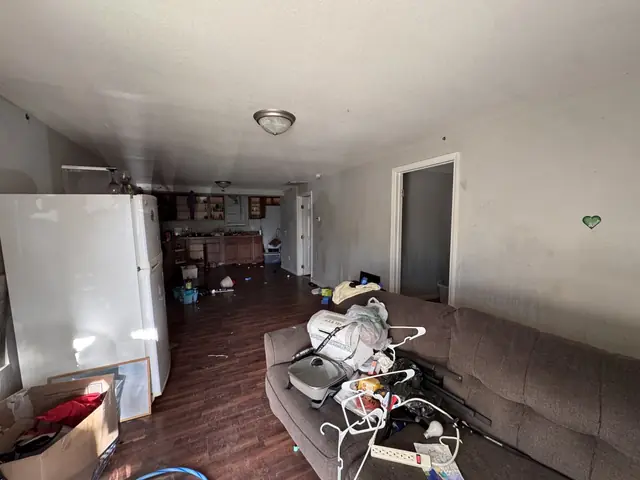 Living room with a couch piled with junk and trash on the floor