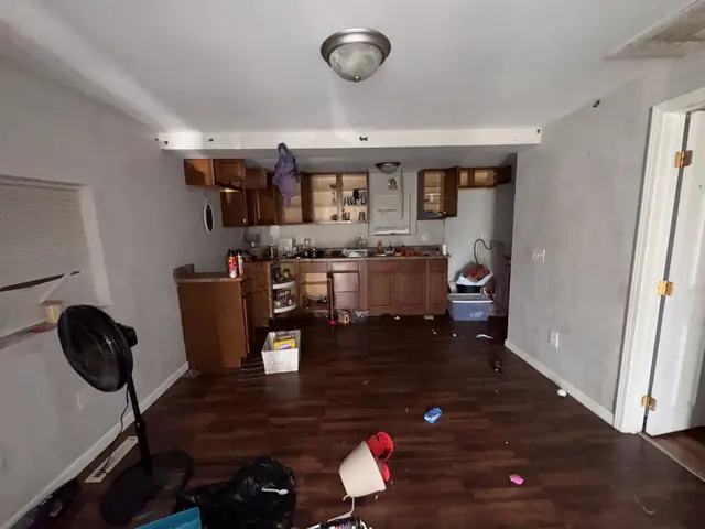 Kitchen with open cabinets and trash on the floor