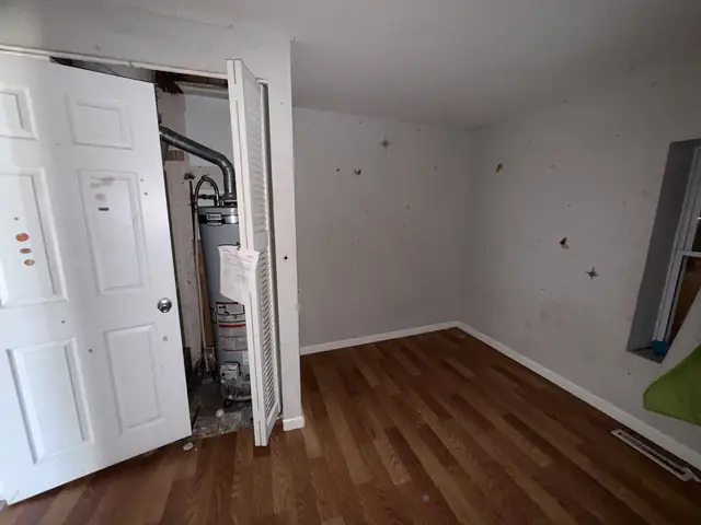 Bedroom with holes in the walls and the water heater closet open