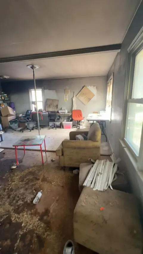 Living room with soot on the walls and debris on the floor